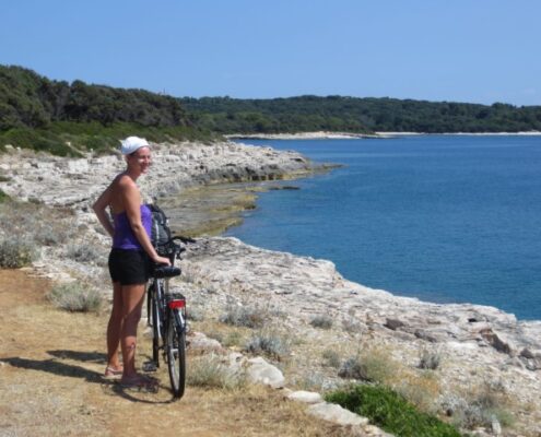 Junge Frau mit Fahrrad an der Küste des Nationalparks Brijuni, Kroatien