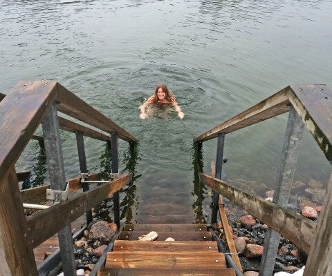 Frau schwimmt im Februar in der Ostsee zum Steg zurück, Finnland