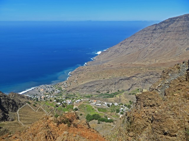 Blick vonb der Küstenstraße über den Ort Tarrafal mit dem blauen Atlantik und kleinen Häusern in einem tief eingeschnittenen Bergtal, Santo Antao, Kapverden