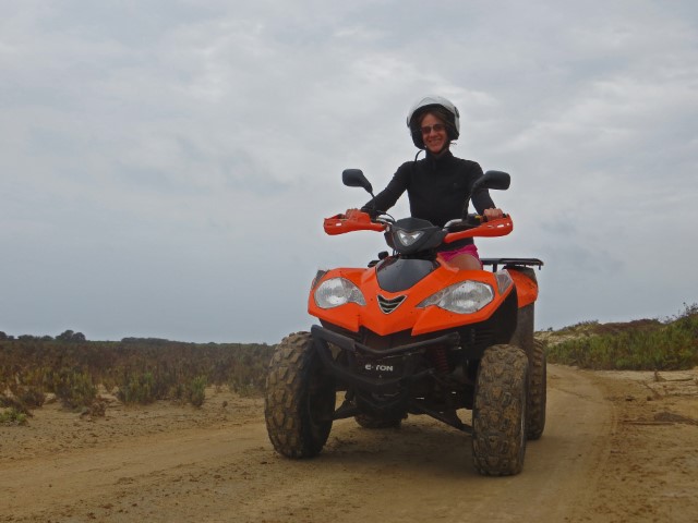 Junge Frau mit Helm und Sonnenbrille auf einem orangenen Quad auf Maio, Kapverden