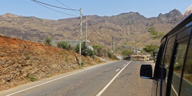 Blick aus dem Busfenster auf eine Straße, umgeben von einer trockenen Berglandschaft, Praia, Kapverden