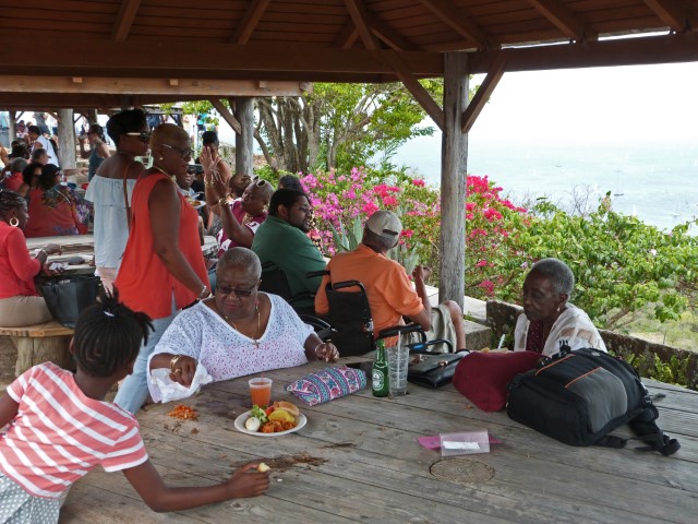 Einheimische Familien essen an Holztischen am Shirley Heights Lookout, Antigua