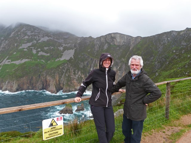 Junge Frau in Anorka und Gästeführer über den wolkenverhangenen Klippen am Slieve League, Donegal, Irland