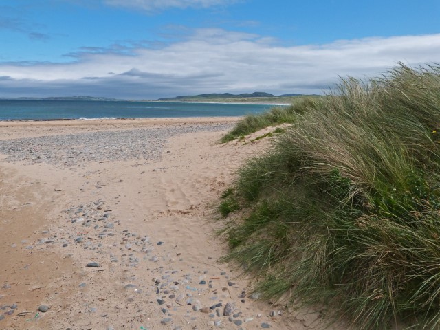 Weißer Strand mit Dünengras und blauem Meer in Donegal, Irland