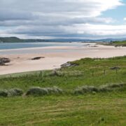 Grüne Wiese, weißer Strand und blaues Meer in Donegal, Irland