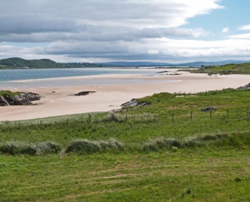 Grüne Wiese, weißer Strand und blaues Meer in Donegal, Irland