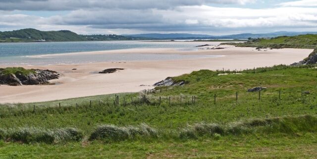 Grüne Wiese, weißer Strand und blaues Meer in Donegal, Irland