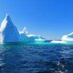 Kleiner Eisberg umgeben von blauem und türkisem Wasser in Neufundland