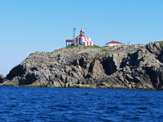 Weiß-rot gestreifter Leuchtturm auf Klippen am Meer, Neufundland