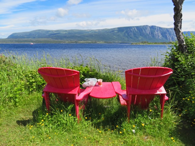 Typisch kanadische rote Stühle mit Blick über den Western Brook Pond und die Berge im Gros Morne Nationalpark Neufundland