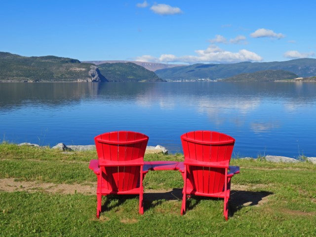 Rote kanadische Stühle an einem See im Gros Morne Nationalpark Neufundland