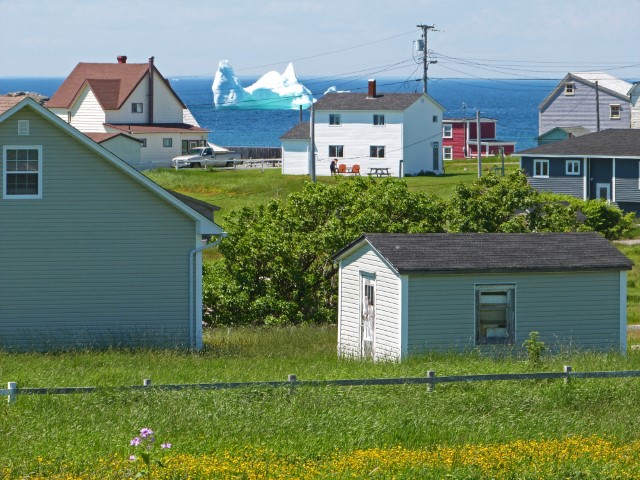 Weiße und bunte Häuser von Bonavista am Meer, auf dem ein Eisberg schwimmt