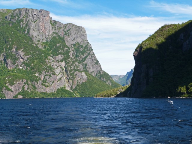 Blick auf hohe Felsen und eine grüne Bergwelt im Fjord des Western Brook Pond im Gros Morne Nationalpark Neufundland