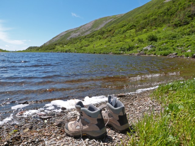 Wanderschuhe an einem kleinen Steinstrand am See im Gros Morne Nationalpark Neufundland