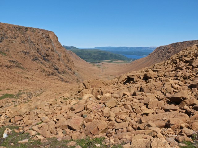 Blick über die Tablelands bis zu einem See und grünen Bergen im Gros Morne Nationalpark Neufundland