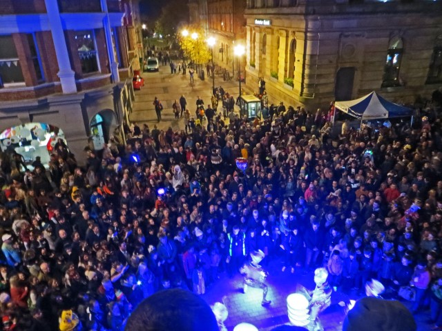 Live-Performer in blauem Licht auf der Straße, umgeben von vielen Leuten an Halloween in Derry, Nordirland