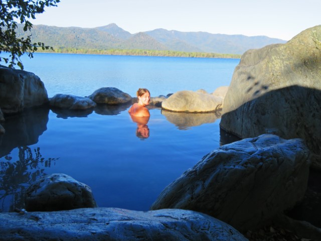 Junge Frau, von der Morgenonne beschienen, sitzt im Onsen am See, Hokkaido, Japan