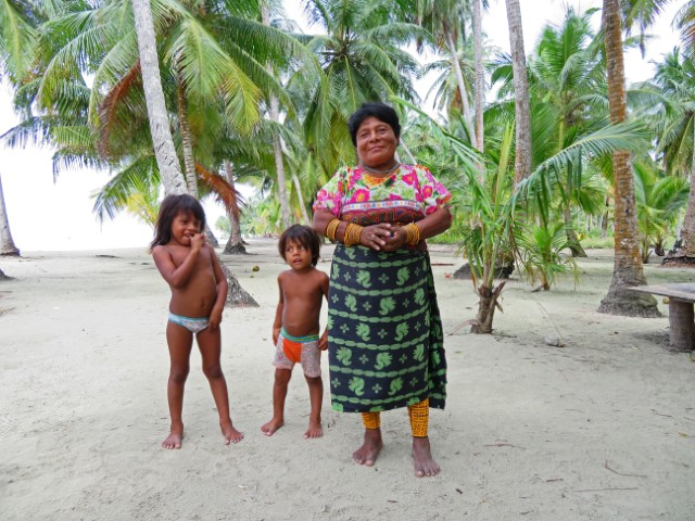 Kuna-Frau in Tracht und zwei halbnackte Kinder am Strand