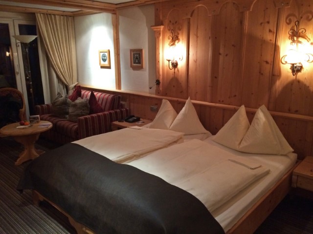 Riesiges Doppelbett und holzvertäfelte Wand im Eermitage Hotel Gstaad