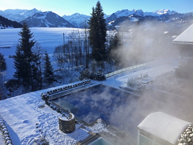 Blick über das heiße Dampfbad des Hotels bis zu den verschneiten Alpen