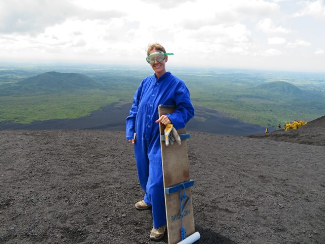 Junge Frau in blauem Anzug, mit Taucherbrille und Brett zum Surfen auf dem Cerro Negro