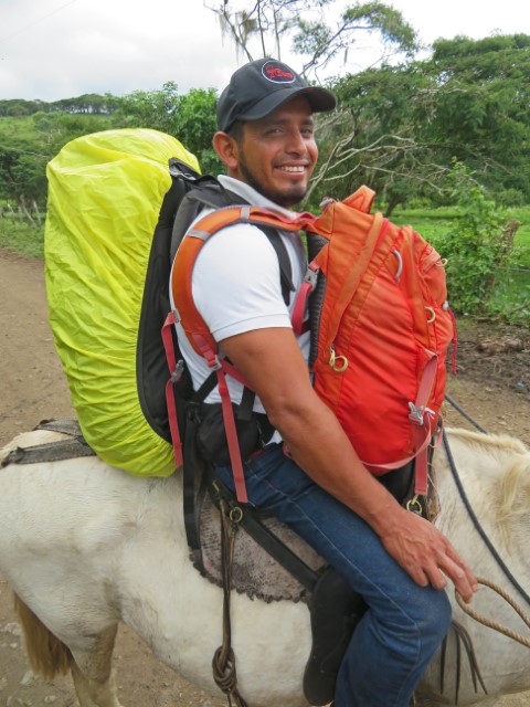 Junger Guide auf Pferd mit einem Rucksack auf dem Rücken und einem vorne