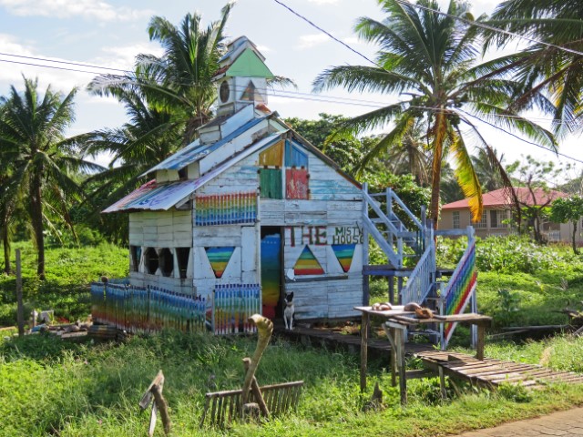 Weißes künstlerisches Haus auf Big Corn Island mit bunten Dreiecken aufgemalt und einem Hund davor