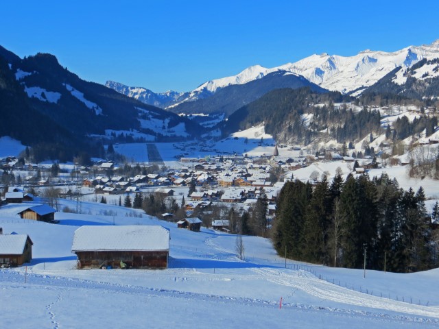 Blick auf die verschneite Landschaft mit hohen Bergen und das Dorf Gstaad