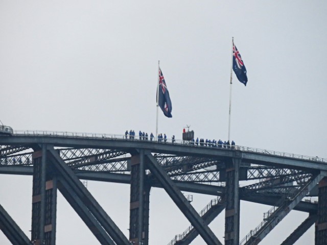 Menschen stehen auf der Sydney Harbour Bridge unter 2 australischen Flaggen