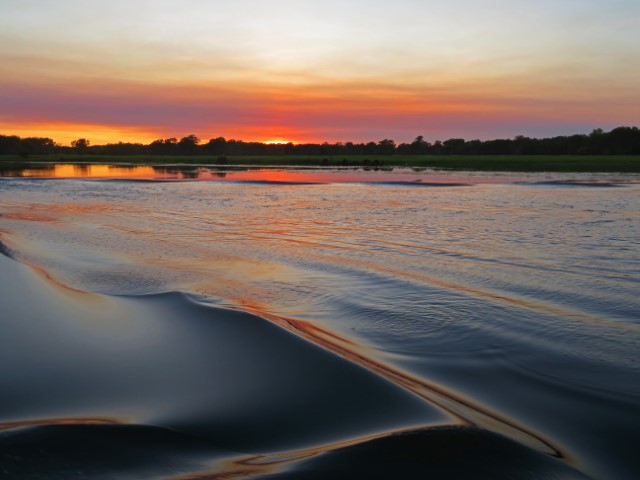 Welliges Wasser und Sonnenaufgang hinter Bäumen in Nordaustralien