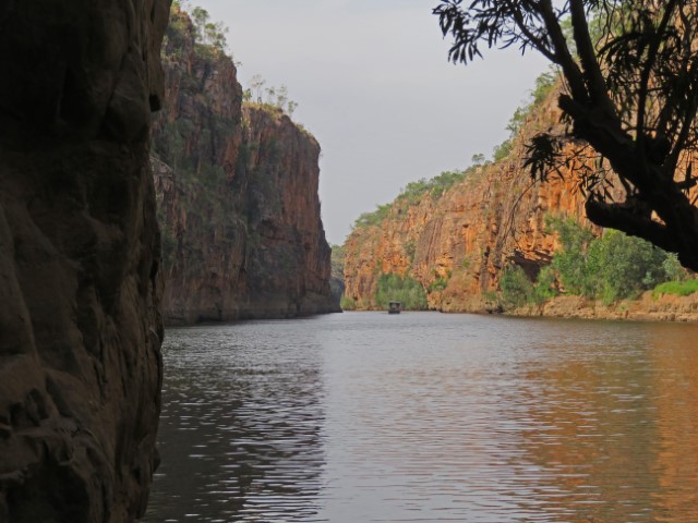 Blick auf den Katherine River mit hohen rötlichen Felswänden und einem Boot in der Ferne