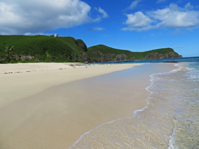 Weißer Sandstrand vor grünen Felsen auf Yasawa Island