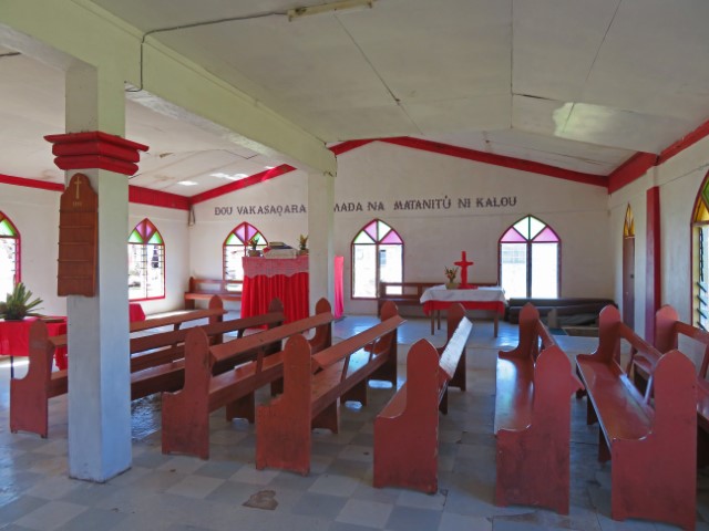 Kirche des Dorfes Bukama auf Yasawa Island mit roten Bänken und weißen Wänden