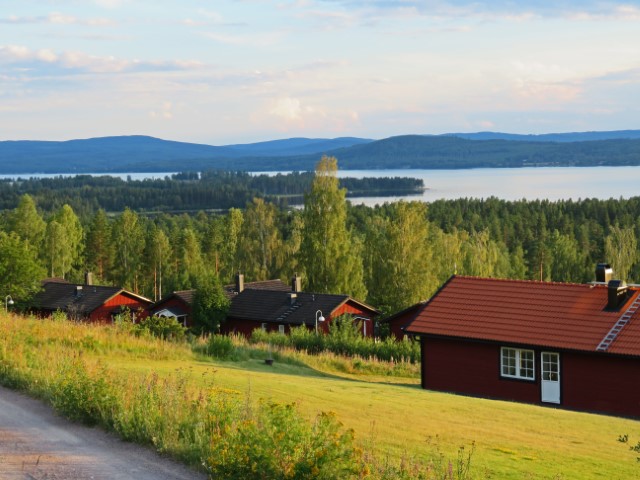 Seenlandschaft mit roten Häusern und frünen Wäldern in Dalarna