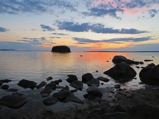 Blick über einen See mit Steinen in Dalarna bei Sonnenuntergang