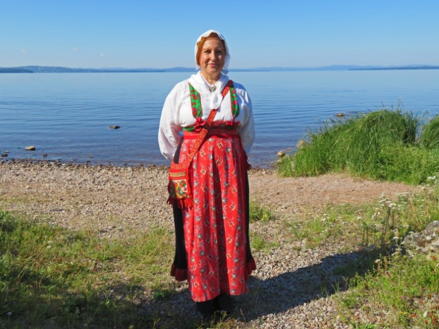 Schwedin in traditioneller Tracht mit rotem Rock und weißer Bluse am Siljansee