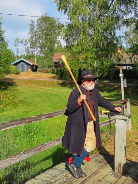 Alter Mann in schwarzer Tracht mit langem Horn in der Hand 