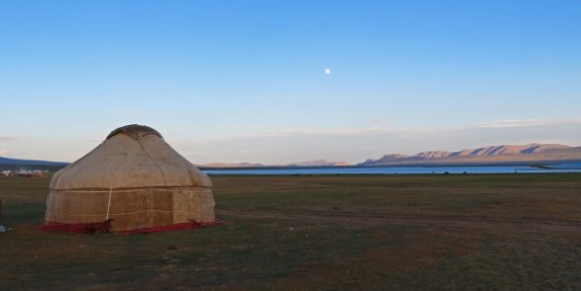 Mond steht am Abendhimmel über dem Song Köl See in Kirgistan, auf der Wiese eine Jurte