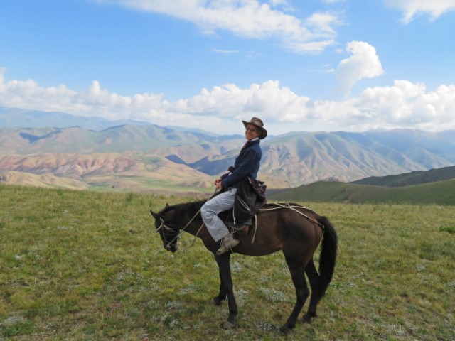 Frau mit Cowboyhut auf einem Pferd in den kirgisischen Bergen