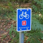 Blaues Schild mit weißem Fahrrad und roter Zahl 8 für den Dänischen Ostseeradweg