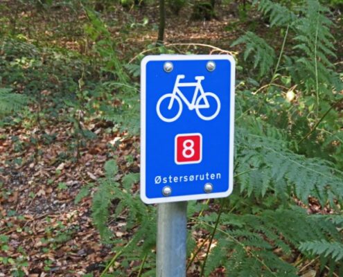 Blaues Schild mit weißem Fahrrad und roter Zahl 8 für den Dänischen Ostseeradweg