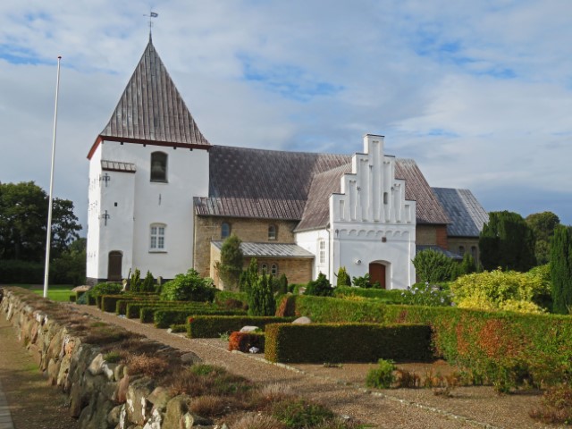 Weiße Kalksteinkirche von Starup mit Friedhof davor