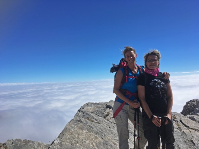 Zwei junge Wanderfrauen auf einem Gipfel, im Hintergrund Wolken