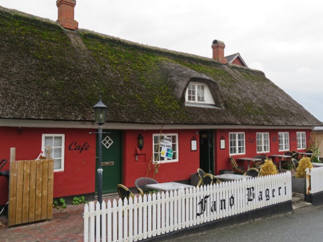 Roters Reetdach-Haus in Nordby auf Fanø, an dessen weißem Zaun Fanø Bageri steht