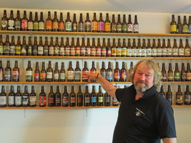 Mann mit Bart vor Regalen voller Bierflaschen im Brauhaus auf Fanø