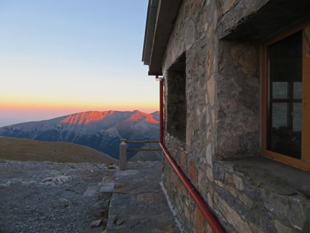 Steinige Apostolidis-Hütte mit Blick auf den Sonnenuntergang hinter den Bergen