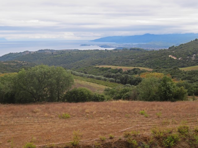 Blick über einen Acker und grüne Landschaft bis zum Meer auf der Chalkidiki-Halbinsel