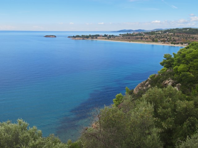 Blick über eine blaue Bucht, umrahmt von begrünten Klippen auf der Chalkidiki-Halbinsel