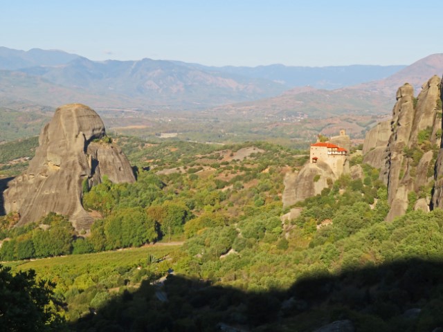 Blick über die grünen Hügel und Berge, in denen auf manchen Felsen die Meteora-Klöster liegen