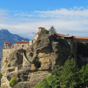 Eins der Meteora-Klöster in Griechenland balanciert auf einer Klippe vor einer Bergkulisse